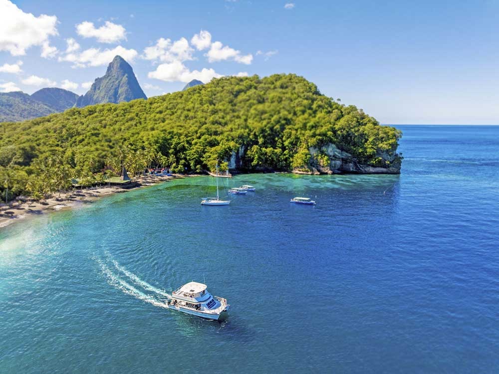 Aerial view of water taxi arriving at Anse Chastanet beach with the Pitons in the background, Saint Lucia